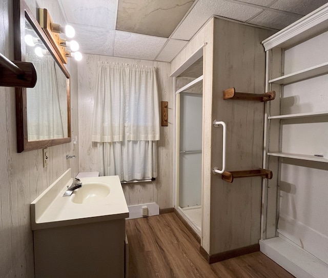 bathroom with a paneled ceiling, vanity, hardwood / wood-style floors, wooden walls, and walk in shower