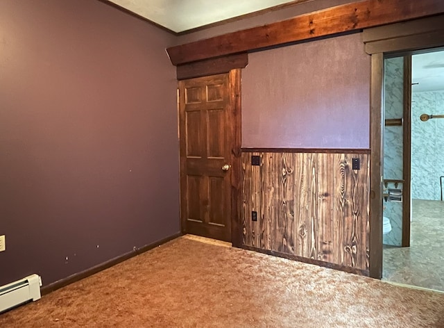 spare room featuring carpet flooring, wood walls, and baseboard heating