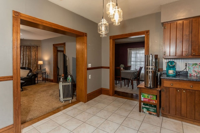 11 Purple St, Wellsboro, PA 16901 - kitchen featuring dark countertops, radiator, light colored carpet, brown cabinets, and light tile patterned flooring