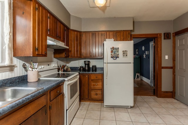 11 Purple St, Wellsboro, PA 16901 - kitchen with white appliances, brown cabinetry, dark countertops, and under cabinet range hood