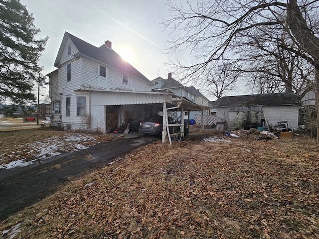 view of property exterior featuring a chimney and a carport