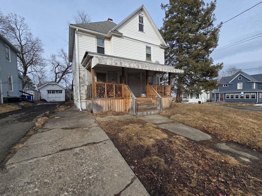 view of front facade featuring a garage, driveway, a porch, and an outdoor structure