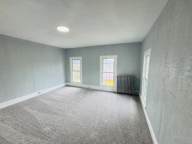 spare room with baseboards, carpet, and radiator