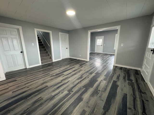 spare room featuring dark wood finished floors, stairway, and baseboards