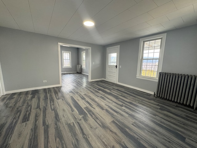 interior space featuring dark wood-style flooring, radiator heating unit, and baseboards