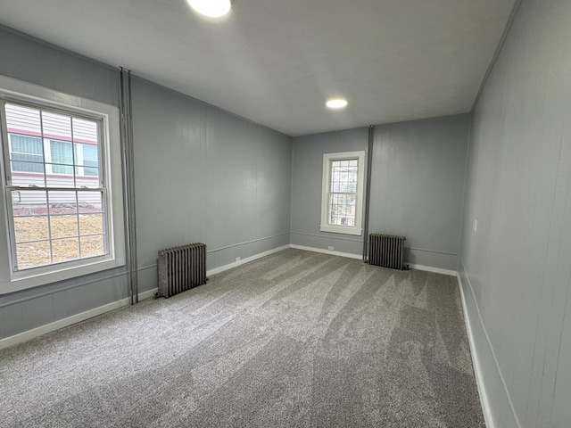 spare room featuring plenty of natural light, radiator heating unit, and carpet flooring