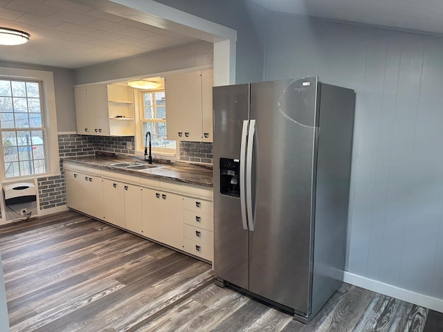 kitchen featuring dark wood-type flooring, a sink, stainless steel refrigerator with ice dispenser, open shelves, and backsplash