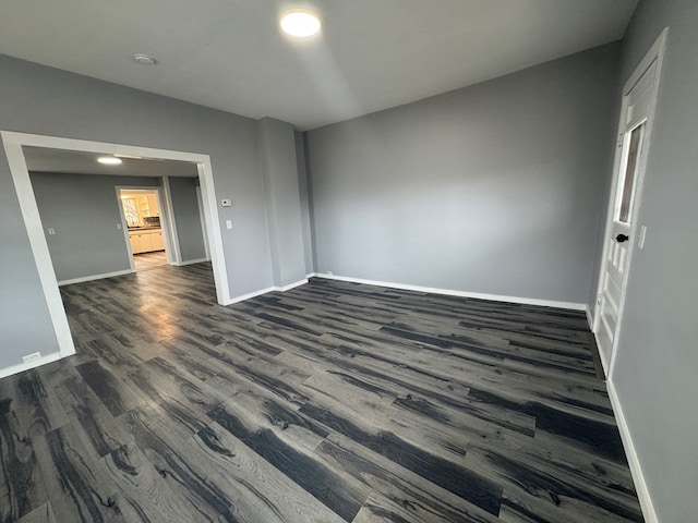 unfurnished room featuring baseboards and dark wood-type flooring