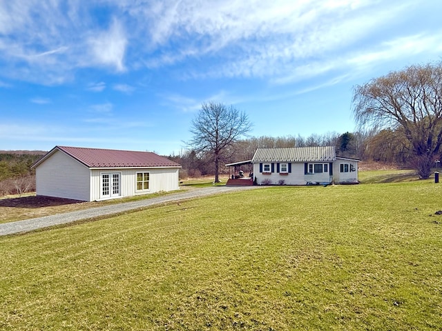 view of front of house featuring french doors, a front yard, dirt driveway, and metal roof