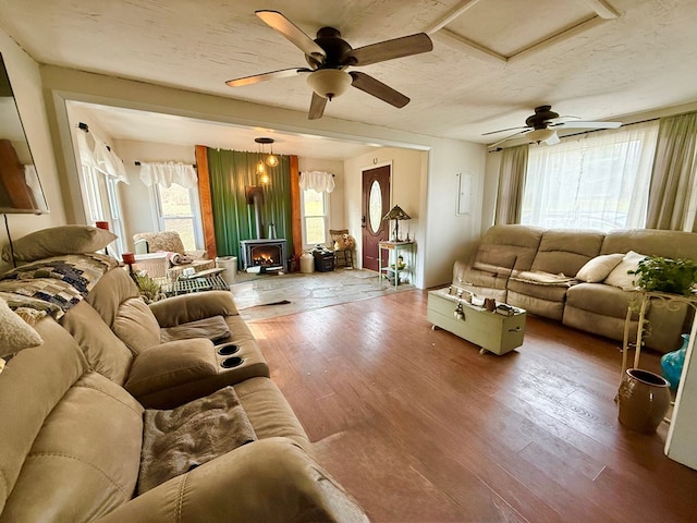 living room with a ceiling fan, wood finished floors, and a textured ceiling