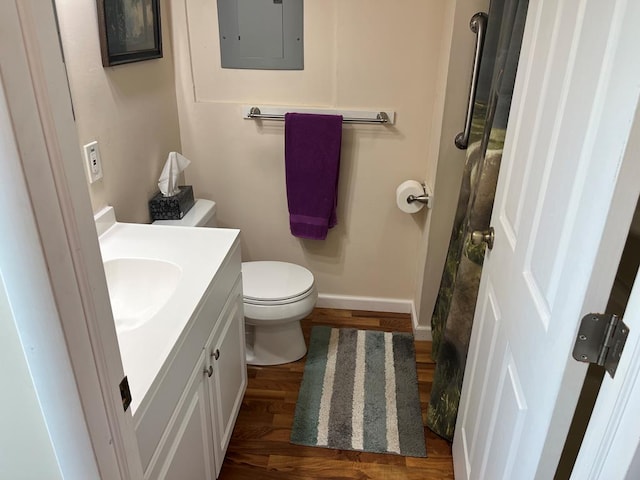 bathroom featuring electric panel, toilet, vanity, and hardwood / wood-style flooring