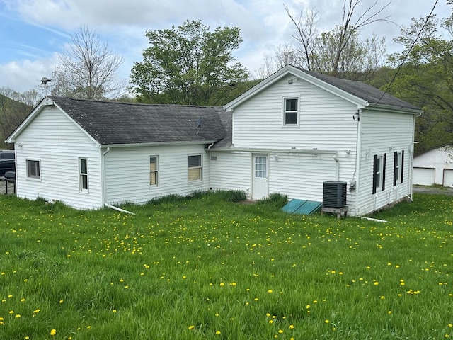 rear view of property featuring central AC unit and a yard