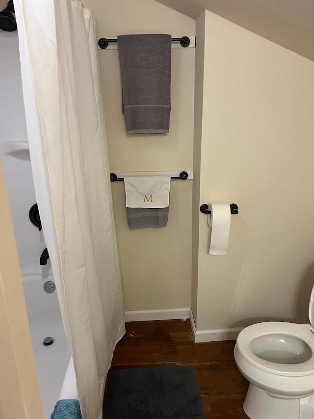 bathroom featuring toilet, wood-type flooring, and vaulted ceiling