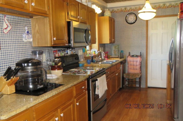 177 Old Barton Rd, Barton, NY 13734 - kitchen featuring appliances with stainless steel finishes, brown cabinetry, a sink, dark wood finished floors, and backsplash