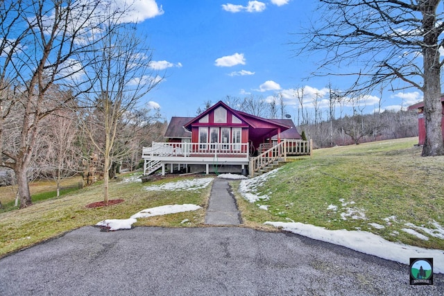 view of front of home with a wooden deck, a front lawn, and a sunroom