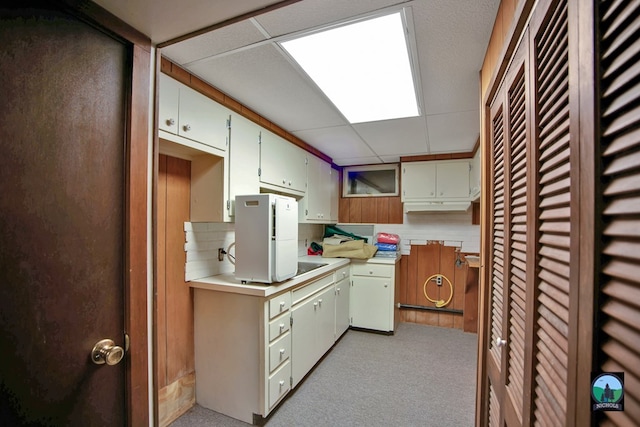 kitchen featuring cream cabinets, light carpet, and a drop ceiling