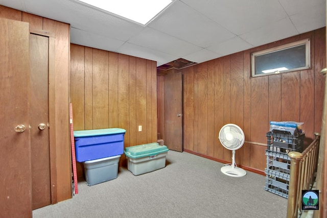 interior space with a paneled ceiling, light carpet, and wooden walls