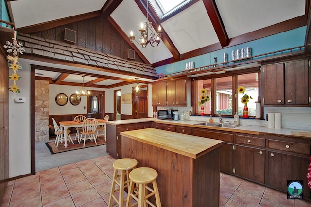 kitchen with sink, a kitchen bar, decorative light fixtures, kitchen peninsula, and a chandelier