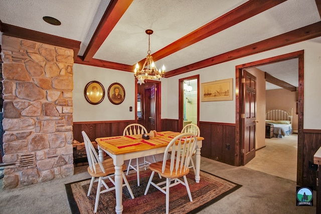 carpeted dining room with beamed ceiling, wooden walls, a chandelier, and a textured ceiling