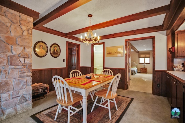 dining room with wood walls, a chandelier, light carpet, a textured ceiling, and beamed ceiling