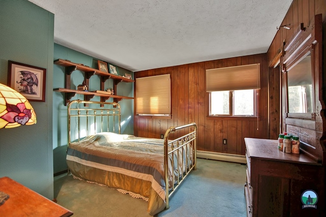 carpeted bedroom featuring a baseboard heating unit, a textured ceiling, and wood walls