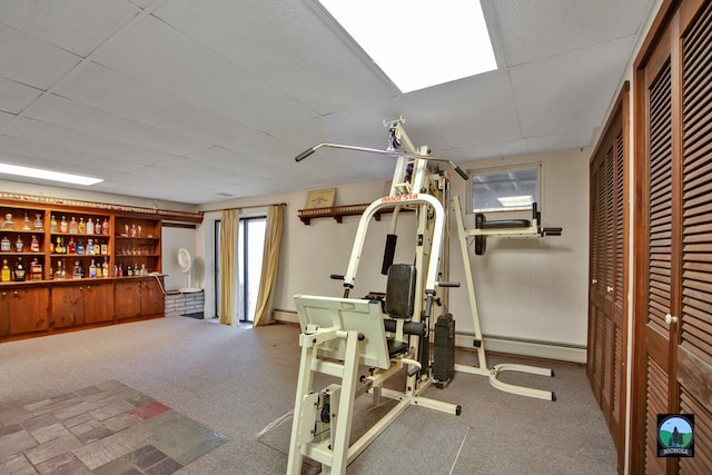 exercise room featuring carpet flooring, indoor bar, a drop ceiling, and baseboard heating