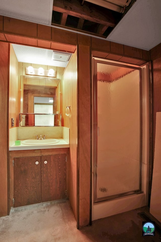 bathroom featuring a shower with door, vanity, and wooden walls