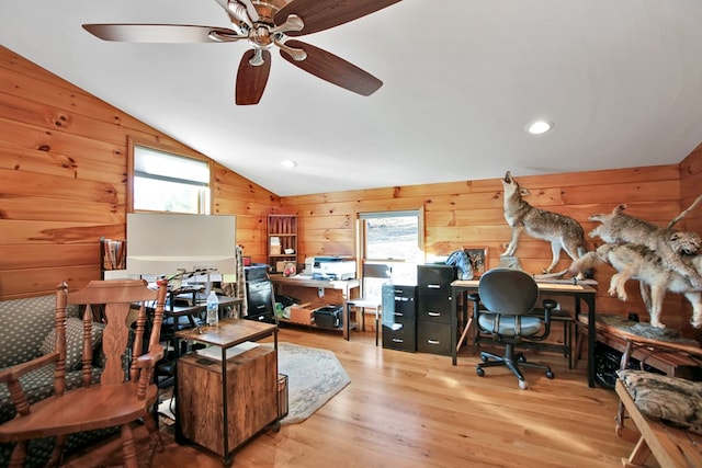 office space featuring a healthy amount of sunlight, wooden walls, vaulted ceiling, and wood finished floors