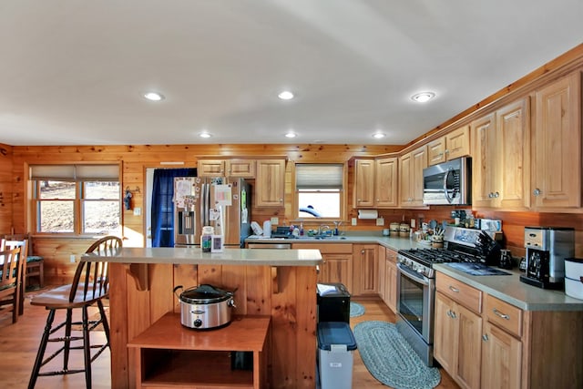 kitchen with appliances with stainless steel finishes, a breakfast bar area, a kitchen island, and light wood-style floors