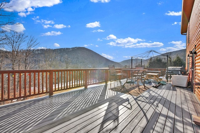 wooden deck featuring outdoor dining area, grilling area, and a mountain view