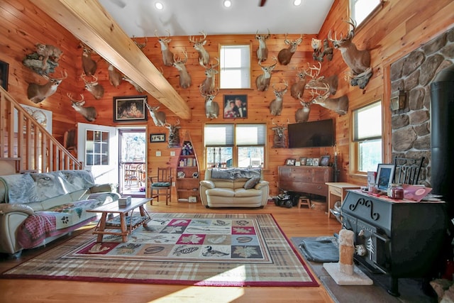 living area with a wood stove, wood walls, a high ceiling, and wood finished floors