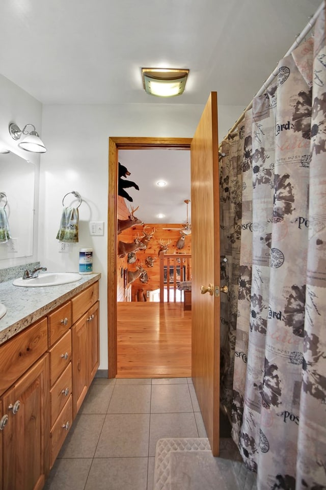 bathroom with double vanity, a shower with curtain, a sink, and tile patterned floors