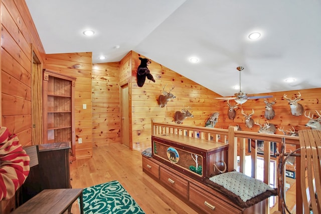 interior space featuring light wood finished floors, recessed lighting, a ceiling fan, vaulted ceiling, and wooden walls