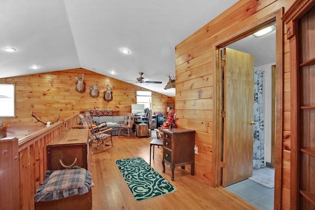 interior space featuring vaulted ceiling, wood walls, wood finished floors, and a ceiling fan