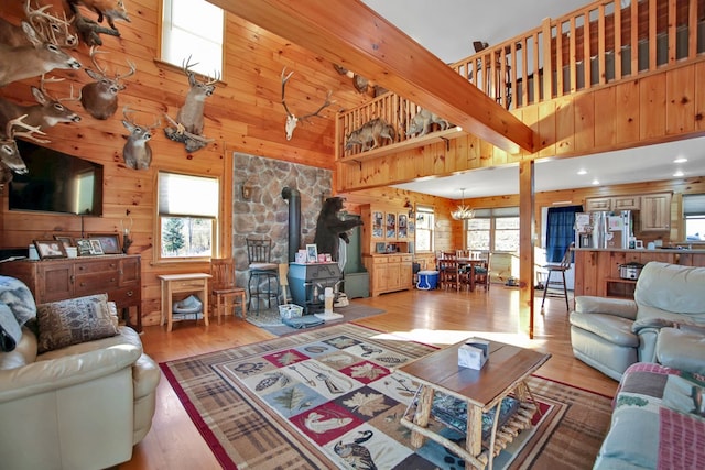 living room with a wood stove, a healthy amount of sunlight, a high ceiling, and wood finished floors