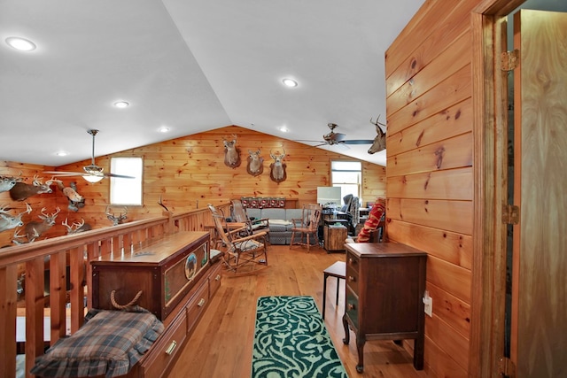 interior space with lofted ceiling, plenty of natural light, light wood-style flooring, and wooden walls