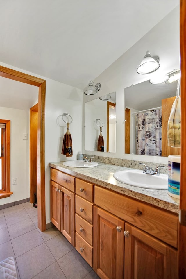 full bath with double vanity, tile patterned flooring, baseboards, and a sink