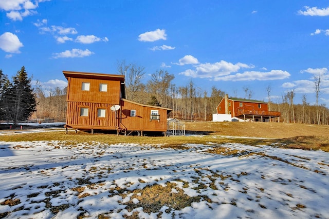 snow covered back of property with a wooden deck