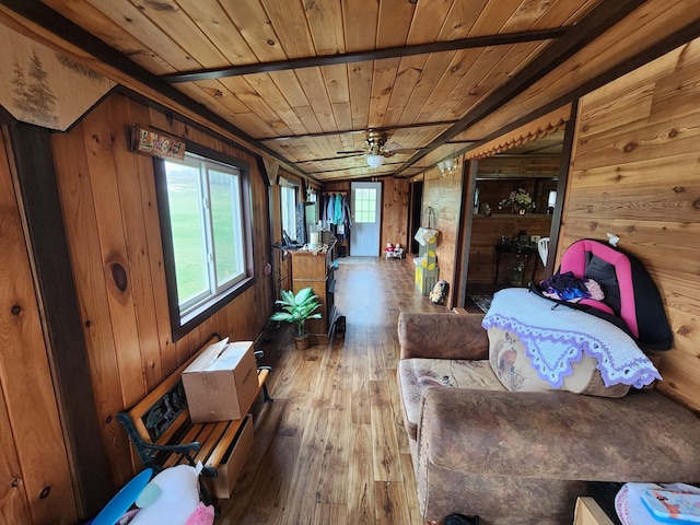 living area featuring a healthy amount of sunlight, wood walls, ceiling fan, and wooden ceiling