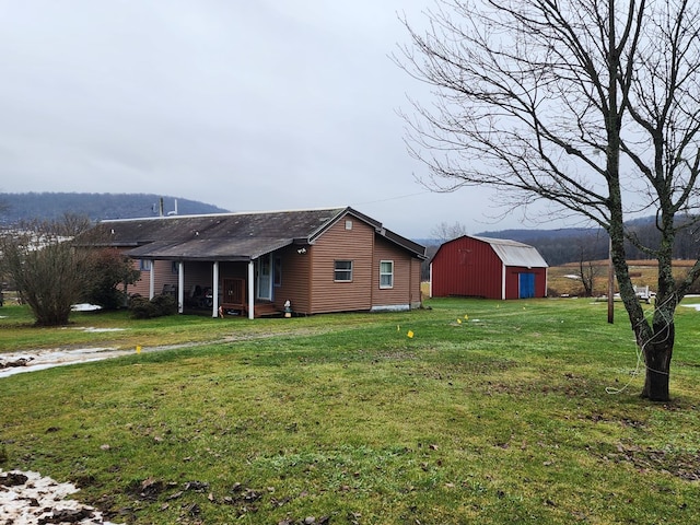 view of property exterior featuring a mountain view, a yard, and a storage unit