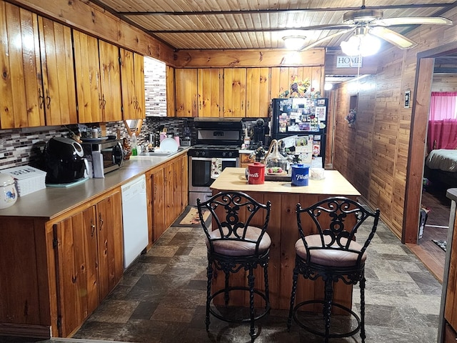 kitchen with wood walls, ceiling fan, stainless steel appliances, and wooden ceiling