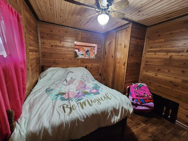 bedroom with ceiling fan, dark hardwood / wood-style floors, wooden ceiling, and wooden walls