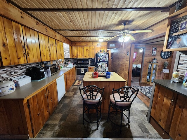 kitchen featuring wood walls, wooden ceiling, sink, ceiling fan, and stainless steel appliances