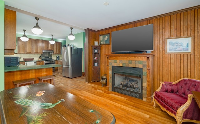 interior space with light hardwood / wood-style floors, wooden walls, and a tiled fireplace