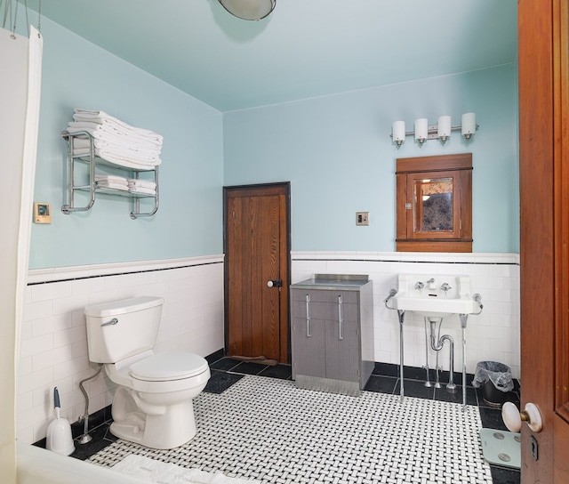 bathroom with toilet, tile walls, and sink