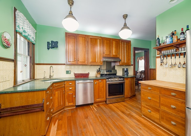 kitchen with decorative light fixtures, sink, light wood-type flooring, and stainless steel appliances