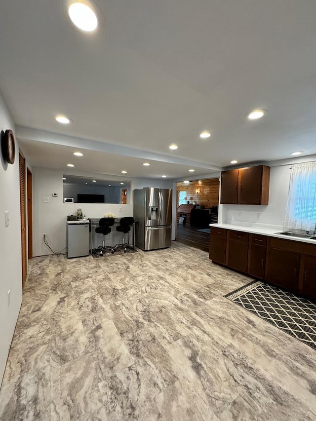 kitchen featuring stainless steel fridge, dark brown cabinetry, and sink