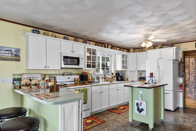 kitchen featuring glass insert cabinets, a center island, white appliances, and white cabinets