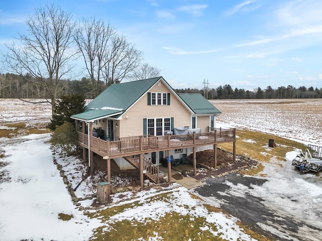 snow covered property featuring metal roof, stairway, and a wooden deck