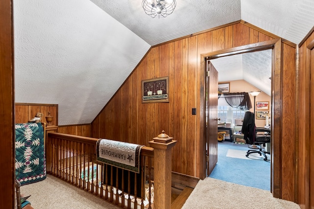 interior space with light carpet, vaulted ceiling, wooden walls, and a textured ceiling